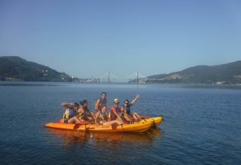 grupo de jovenes en una actividad con kayaks autovaciables, en la ensenada de san simon, con el puente de rande al fondo